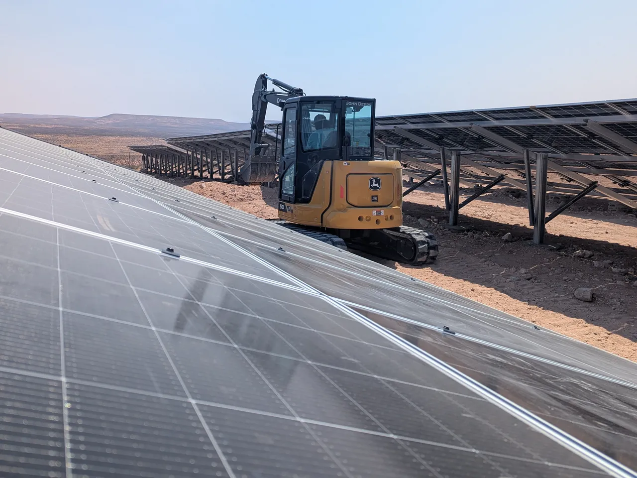 John Deere 50P working between rows of solar panels